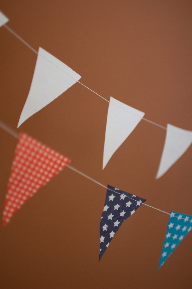 WHITE PAPER FLAG GARLAND ON A WOODEN SPOOL